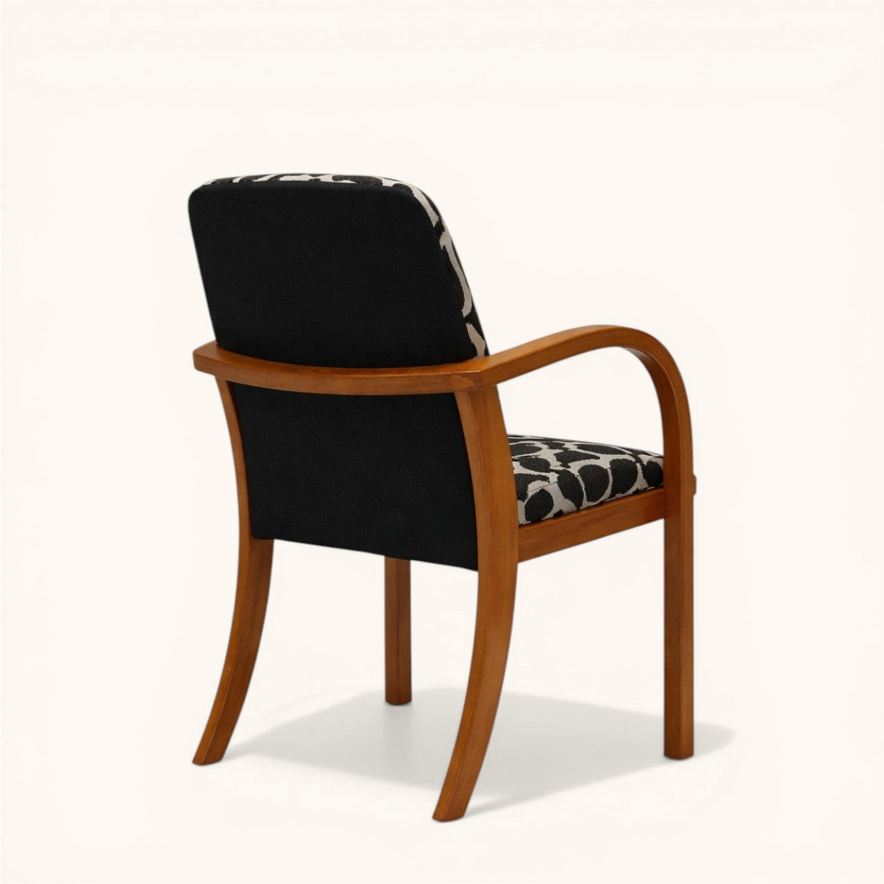 Stuhl mit Holzgestell, geschwungenen Armlehnen und schwarz-cremefarben gemusterter Polsterung an Sitz und Rückenlehne, markanter Designerstuhl