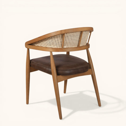 Eleganter Esszimmerstuhl aus Holz mit brauner Kunstlederpolsterung, geflochtener Rückenpartie und modernem Design.