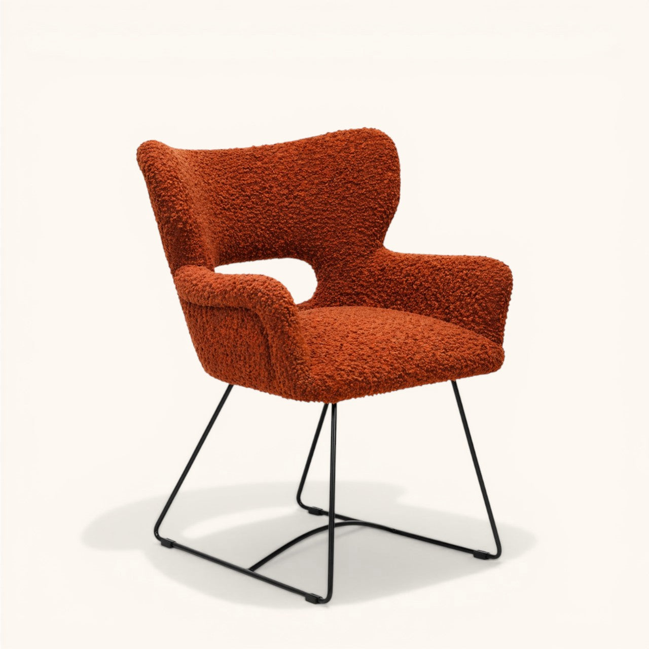 Stuhl mit orangefarbenem Bouclé-Bezug, gerundeter Rückenlehne mit offener Aussparung, integrierten Armlehnen und schwarzem Metallgestell, moderner Designerstuhl