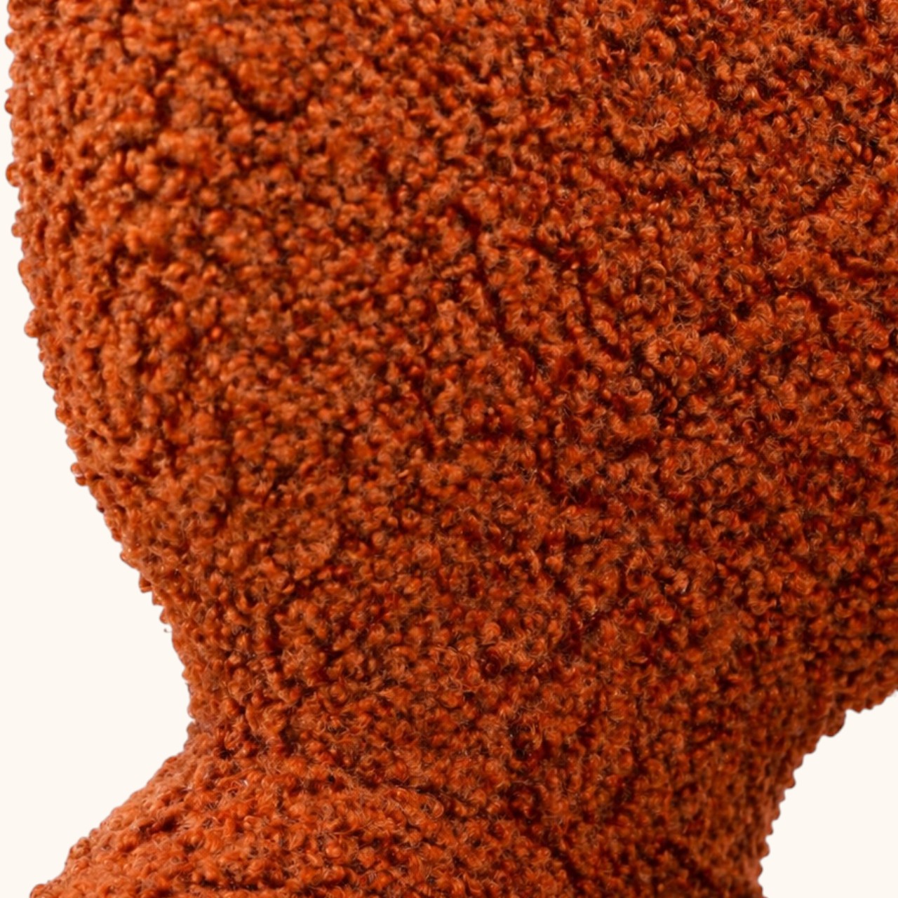 Stuhl mit orangefarbenem Bouclé-Bezug, gerundeter Rückenlehne mit offener Aussparung, integrierten Armlehnen und schwarzem Metallgestell, moderner Designerstuhl